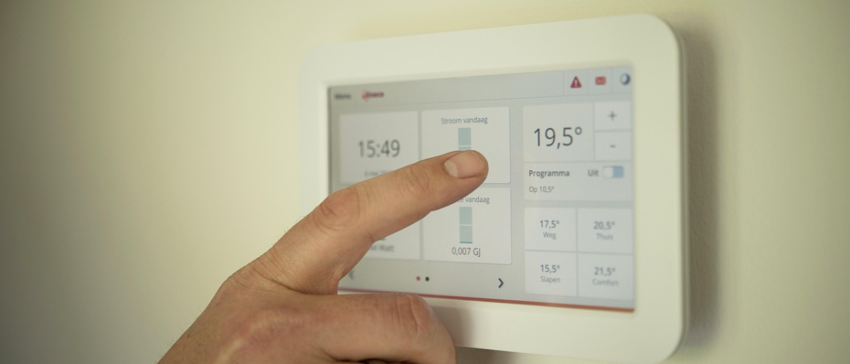 Hand bedient digitales Smart Home Thermostat zur Steuerung der Raumheizung und Kontrolle des aktuellen Energieverbrauchs.