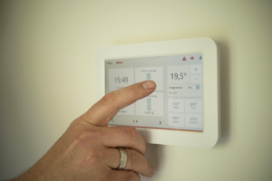 Hand bedient digitales Smart Home Thermostat zur Steuerung der Raumheizung und Kontrolle des aktuellen Energieverbrauchs.