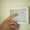 Hand bedient digitales Smart Home Thermostat zur Steuerung der Raumheizung und Kontrolle des aktuellen Energieverbrauchs.