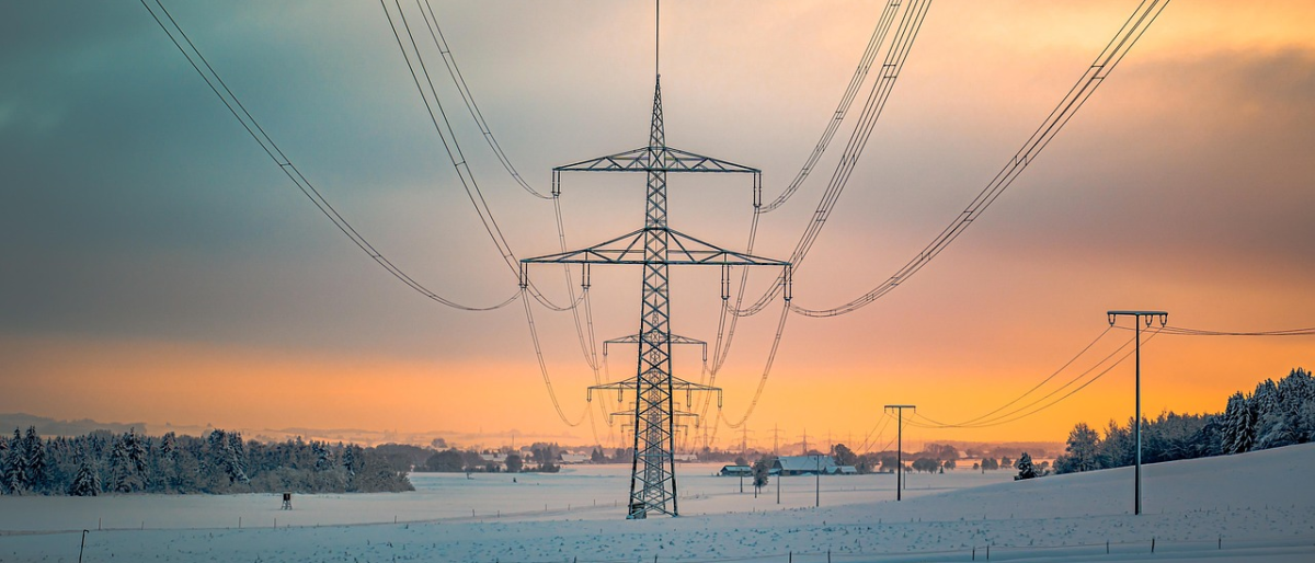 Versorgungssicherheit der Schweiz - Sonnenuntergang im Hintergrund, davor ein Strommast mit Leitungen, die auf den Betrachter zu laufen