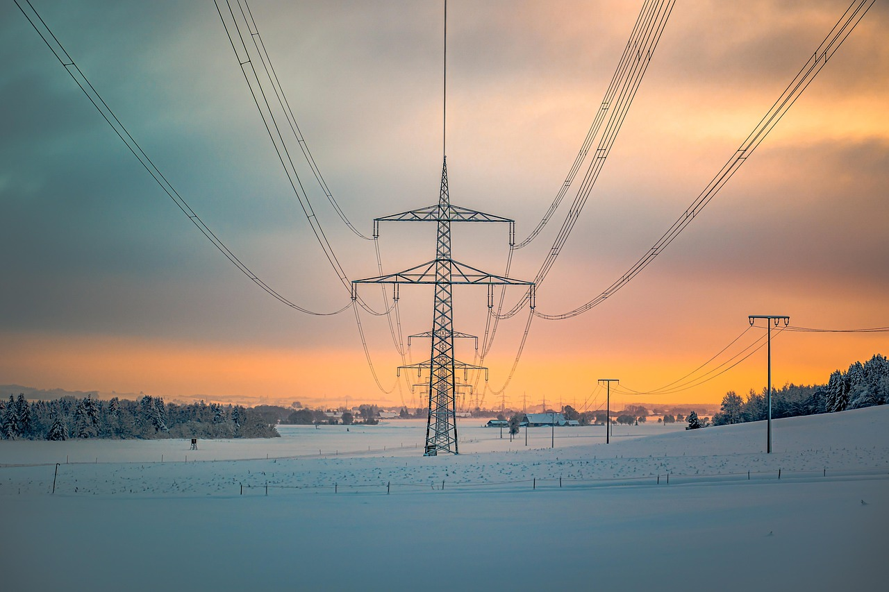 Versorgungssicherheit der Schweiz - Sonnenuntergang im Hintergrund, davor ein Strommast mit Leitungen, die auf den Betrachter zu laufen